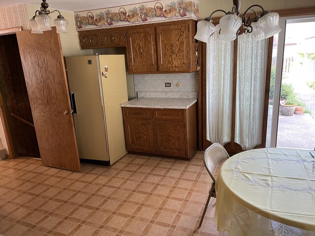7236 W Olive Ave, Chicago, IL 60631 - kitchen with an inviting chandelier, freestanding refrigerator, light floors, light countertops, and backsplash