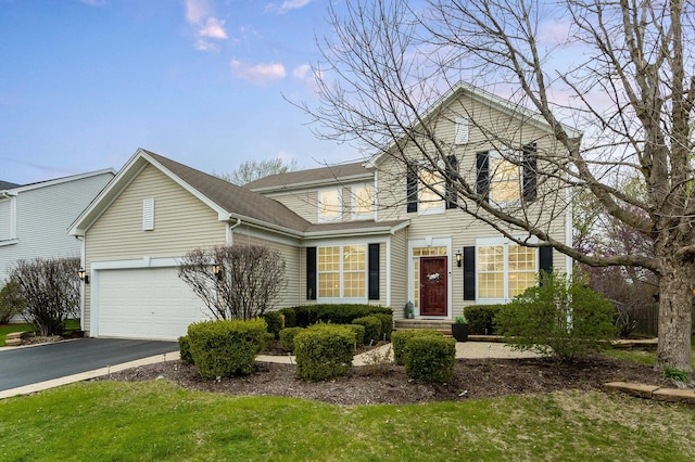 traditional-style house featuring an attached garage, driveway, and a front yard