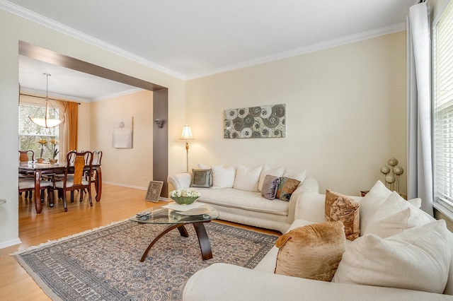 living room with crown molding, baseboards, and light wood-style floors