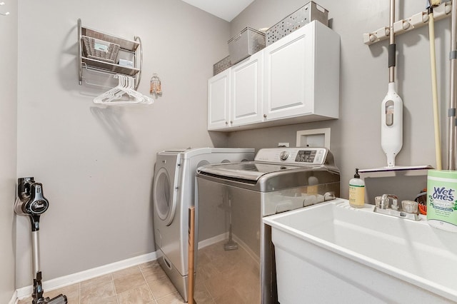 washroom with cabinet space, separate washer and dryer, baseboards, and a sink