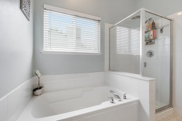 full bath featuring plenty of natural light, a stall shower, and a garden tub