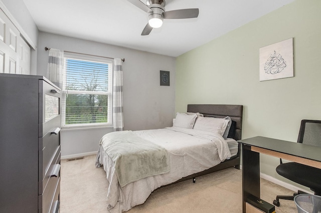 bedroom with baseboards, a ceiling fan, visible vents, and light carpet