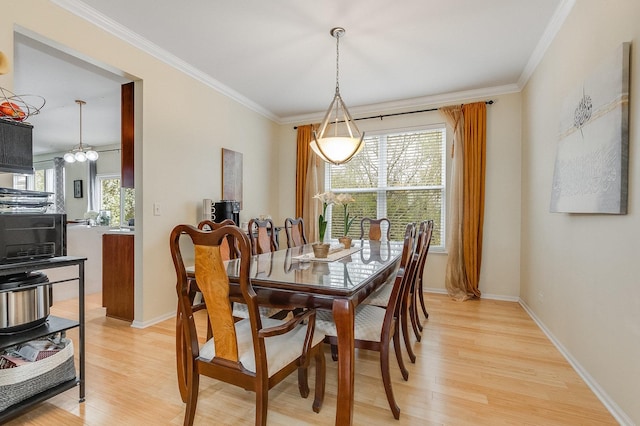dining room featuring crown molding, baseboards, and light wood-style flooring