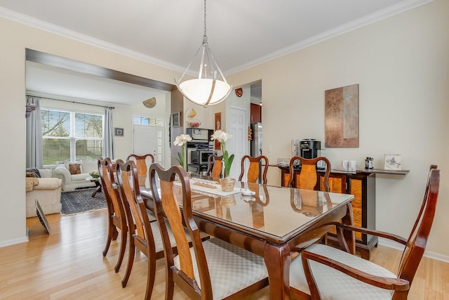 dining space featuring crown molding, baseboards, and light wood-type flooring
