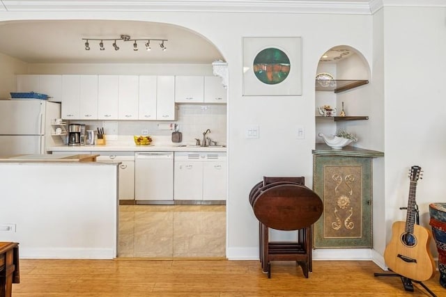 kitchen with light countertops, a sink, white cabinets, and white appliances
