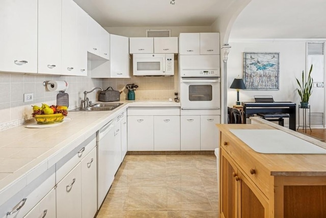 kitchen featuring backsplash, visible vents, a sink, white appliances, and white cabinetry