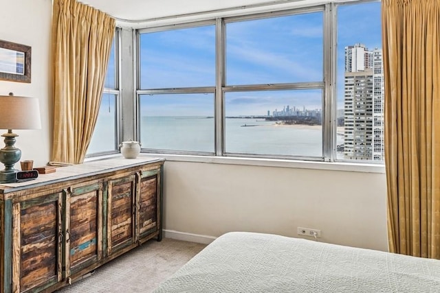bedroom with light colored carpet, a city view, a water view, and multiple windows