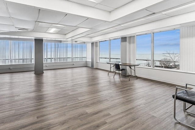 interior space with baseboards, a water view, and wood finished floors