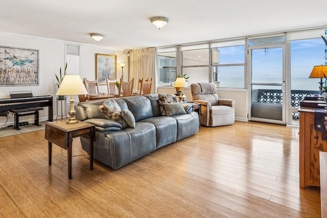 living room featuring light wood-style floors, ornamental molding, and baseboards