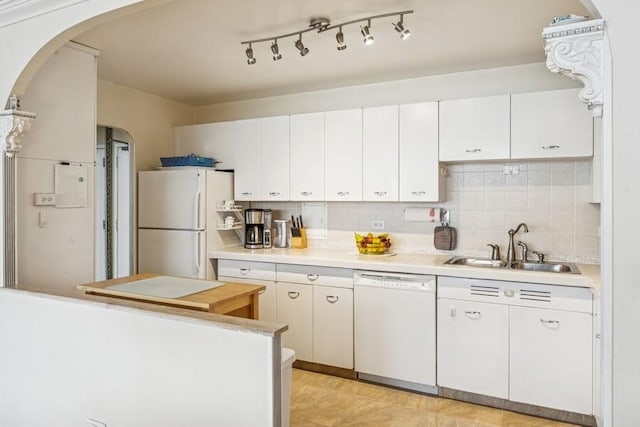 kitchen featuring a sink, white appliances, light countertops, white cabinets, and arched walkways