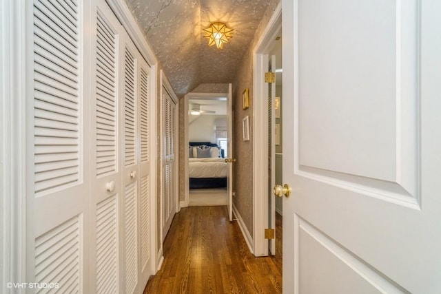 hall with lofted ceiling and dark wood finished floors
