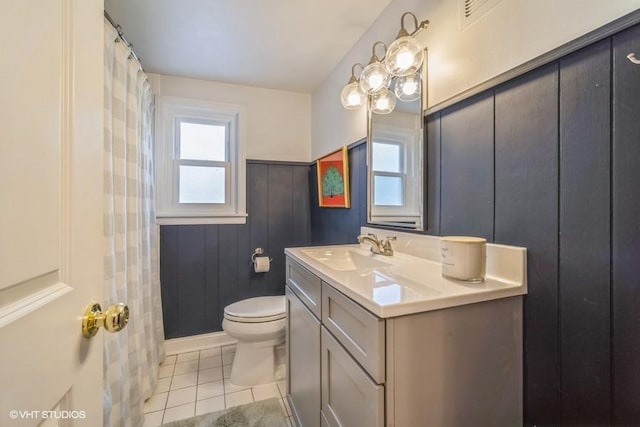 full bathroom with toilet, wainscoting, tile patterned flooring, and vanity