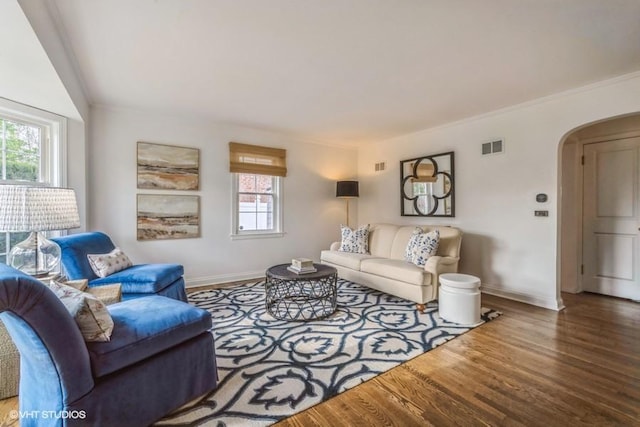living area with a wealth of natural light, arched walkways, baseboards, and wood finished floors