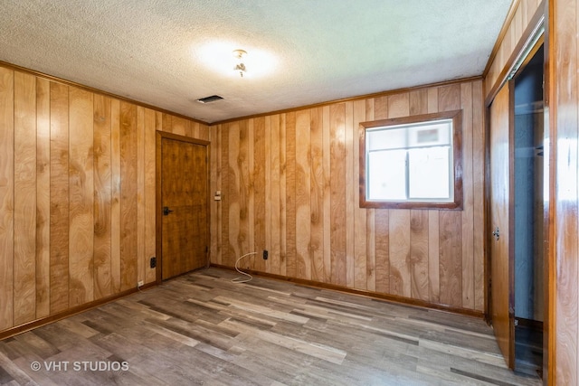 21822 Merrill Ave, Sauk Village, IL 60411 - empty room with wood finished floors, a textured ceiling, wood walls, and baseboards