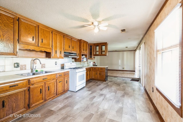 21822 Merrill Ave, Sauk Village, IL 60411 - kitchen featuring white gas range oven, a sink, brown cabinets, under cabinet range hood, and a textured ceiling