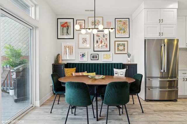 dining space with baseboards, visible vents, and light wood-style flooring