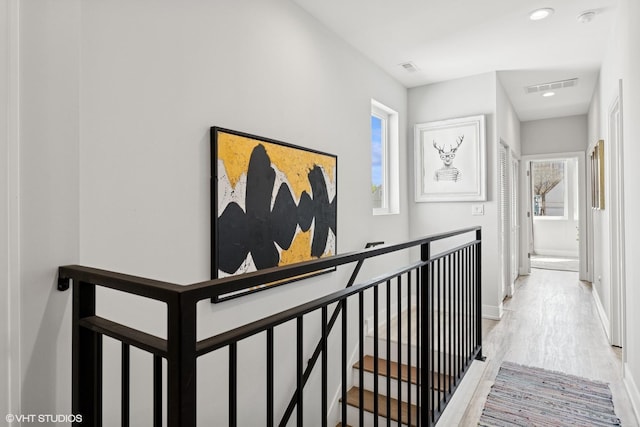 hallway featuring an upstairs landing, plenty of natural light, wood finished floors, and visible vents