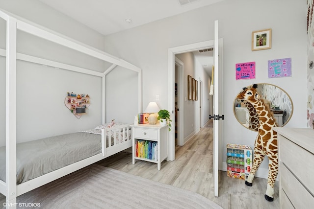 bedroom featuring baseboards, light wood-style flooring, and visible vents