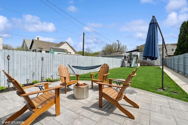 view of patio featuring a playground, an outdoor fire pit, and a fenced backyard