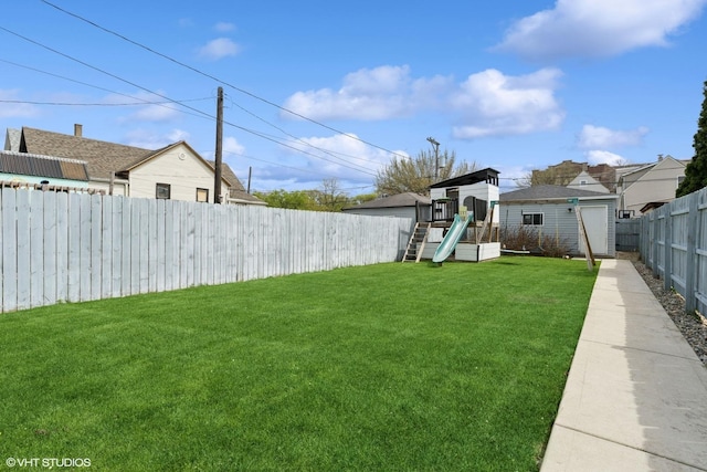 view of yard featuring an outbuilding, a fenced backyard, a playground, and a shed