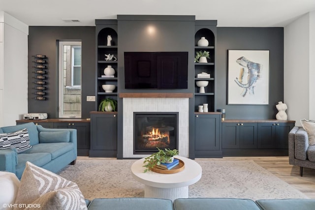 living room featuring a tile fireplace, wood finished floors, and visible vents