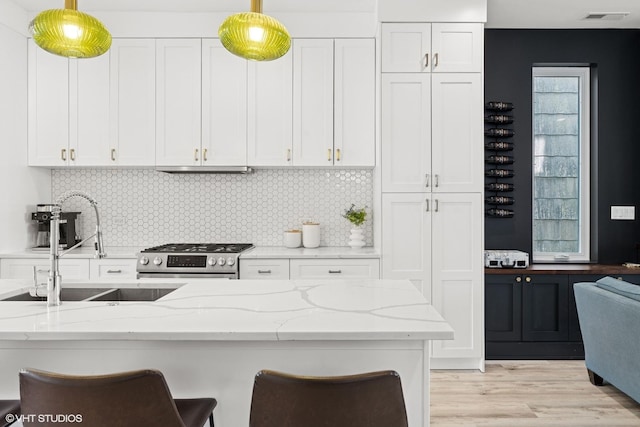kitchen featuring gas stove, white cabinetry, a sink, and visible vents