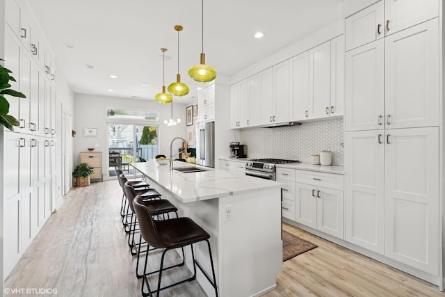 kitchen featuring white cabinetry, appliances with stainless steel finishes, decorative backsplash, and light wood-style floors