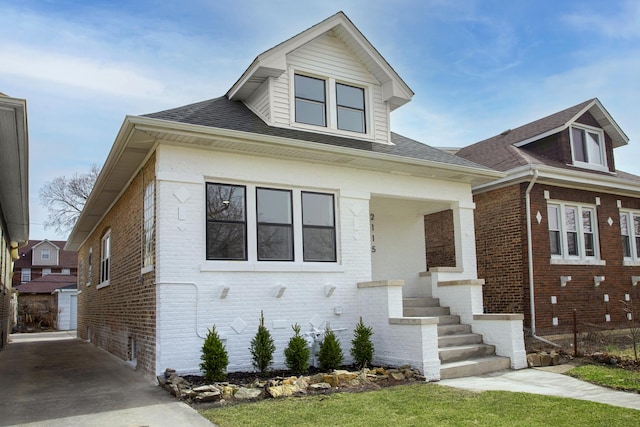 bungalow-style house with roof with shingles and brick siding