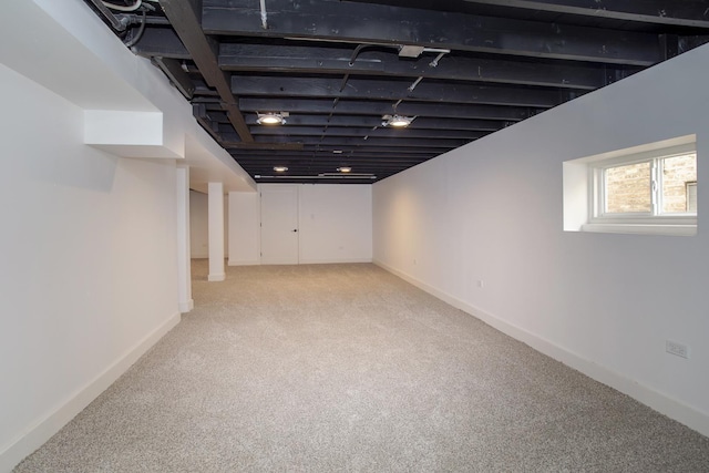 below grade area with baseboards and light carpet