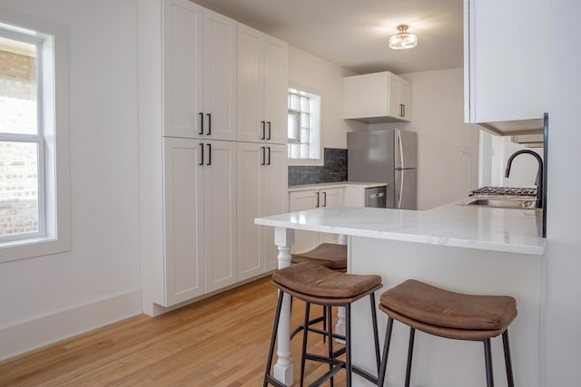 kitchen featuring freestanding refrigerator, backsplash, a breakfast bar, and a sink