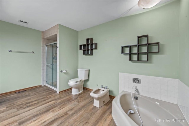 bathroom with a bath, visible vents, a stall shower, wood finished floors, and toilet