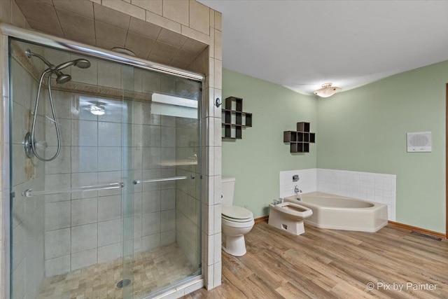 bathroom with baseboards, a stall shower, toilet, and wood finished floors