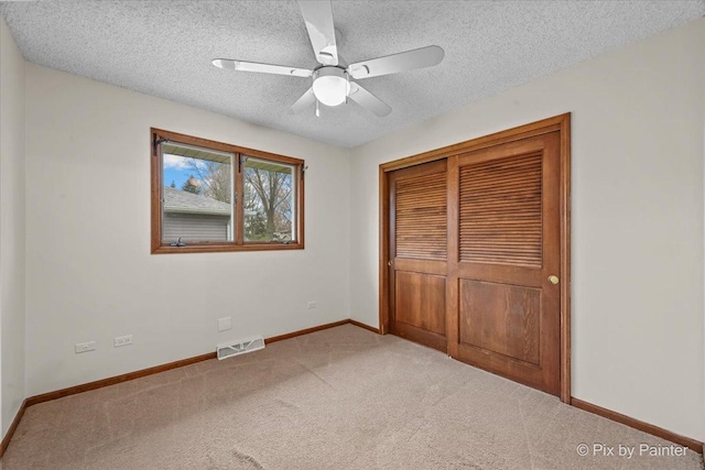 unfurnished bedroom with carpet flooring, a textured ceiling, baseboards, visible vents, and a closet