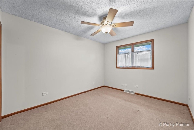 carpeted spare room with visible vents, a textured ceiling, baseboards, and ceiling fan