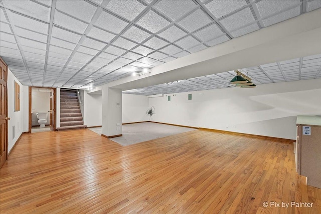 finished basement featuring wood-type flooring, baseboards, and stairway