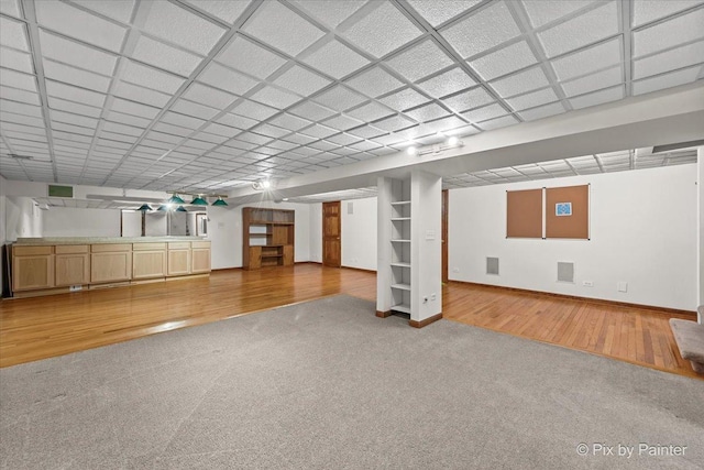 finished below grade area with carpet floors, baseboards, wood finished floors, and visible vents