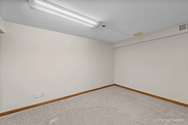 carpeted spare room with visible vents and baseboards