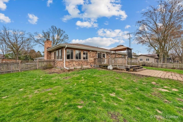 back of property featuring a deck, a fenced backyard, a chimney, a gazebo, and a lawn