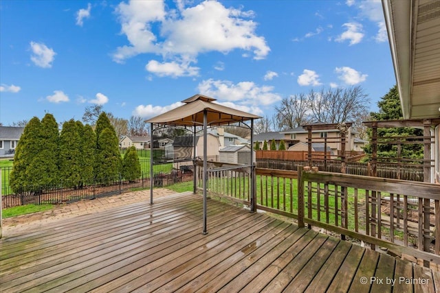 wooden deck with a residential view, a storage shed, a fenced backyard, a lawn, and an outdoor structure