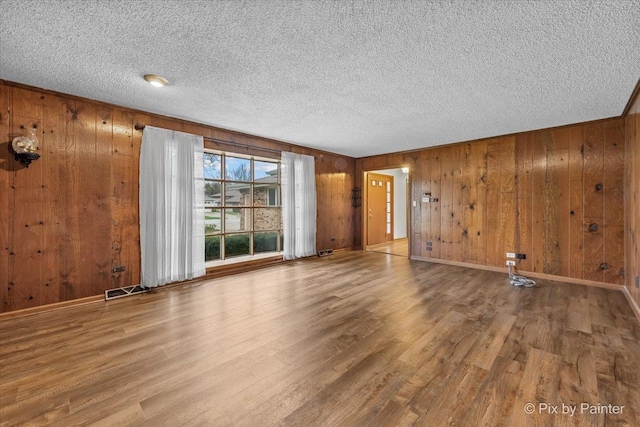 empty room featuring visible vents, a textured ceiling, and wood finished floors