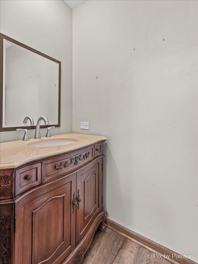 bathroom with baseboards, wood finished floors, and vanity