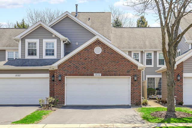 view of front of house with brick siding, driveway, a shingled roof, and a garage