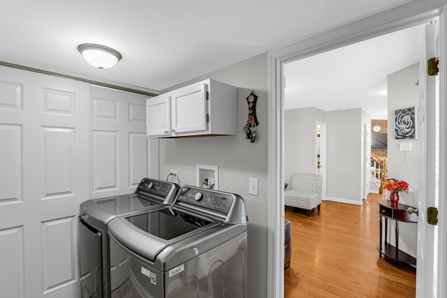laundry area with separate washer and dryer, light wood-style flooring, cabinet space, and baseboards