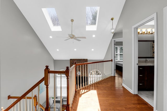 corridor featuring a sink, recessed lighting, an upstairs landing, wood finished floors, and lofted ceiling with skylight