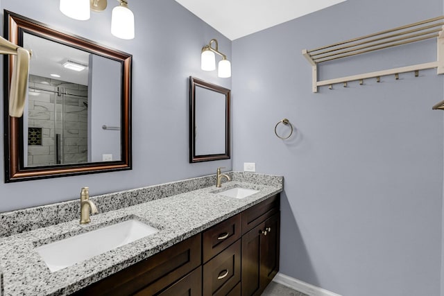 bathroom featuring double vanity, baseboards, tiled shower, and a sink