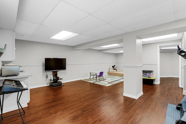 interior space with baseboards, a drop ceiling, and wood finished floors