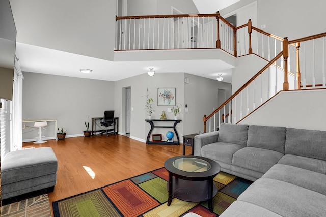 living room featuring baseboards, stairs, a towering ceiling, and wood finished floors