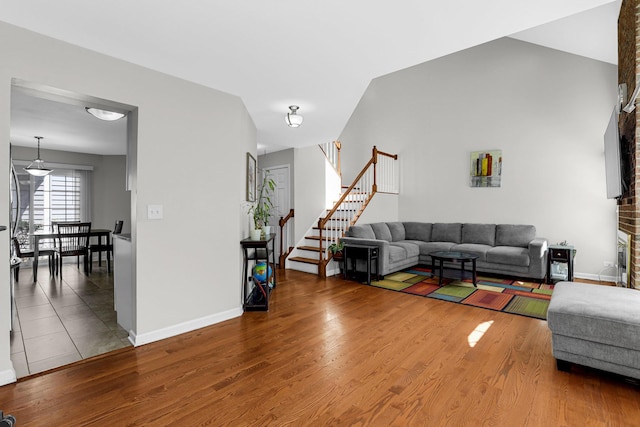 living room featuring baseboards, stairs, and wood finished floors