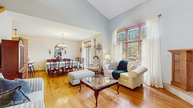 living area featuring high vaulted ceiling, ornamental molding, light wood finished floors, and a notable chandelier