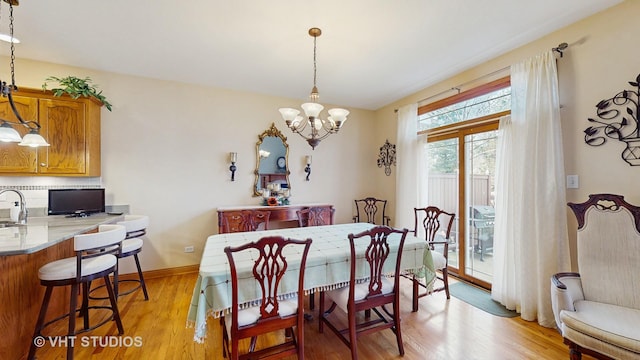 dining area with baseboards, a chandelier, and light wood-style flooring
